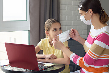 Image showing Girl at home puts on protective medical mask to child