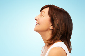 Image showing profile of smiling senior woman over blue