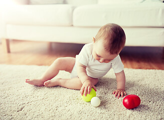 Image showing happy baby playing with balls on floor at home