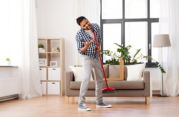 Image showing man with broom cleaning and singing at home