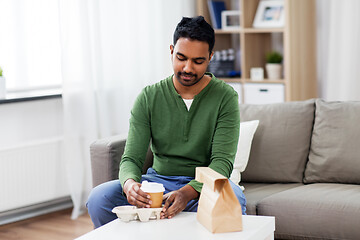 Image showing indian man with takeaway coffee and food at home