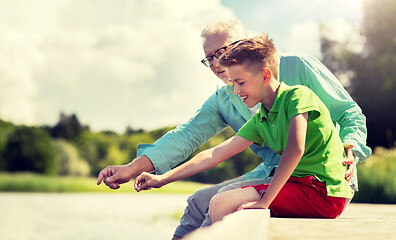 Image showing grandfather and grandson sitting on river berth