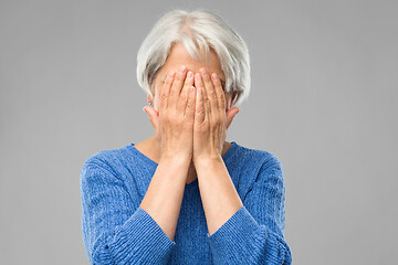 Image showing stressed senior woman holding to her head