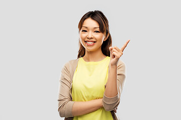 Image showing happy asian woman pointing finger up