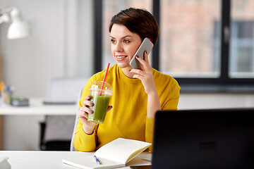 Image showing woman with drink calling on smartphone at office