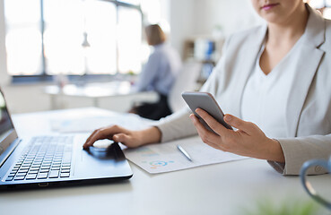 Image showing businesswoman with smartphone and laptop at office