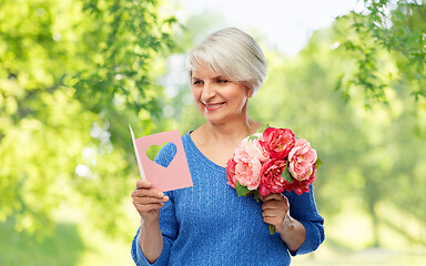 Image showing happy senior woman with flowers and greeting card