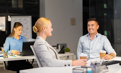 Image showing business people drinking coffee at night office