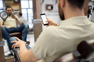 Image showing close up of man with smartphone at barbershop