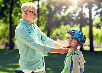 Image showing old man helping boy with bike helmet at park