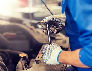 Image showing mechanic man with wrench repairing car at workshop