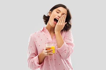 Image showing happy yawning young woman in pajama with juice