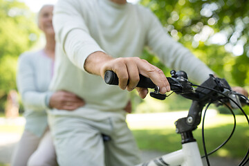 Image showing happy senior couple riding one bicycle at park