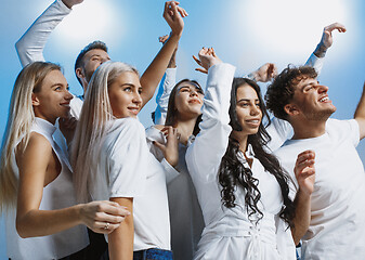 Image showing Group of cheerful joyful young people standing and celebrating together over blue background