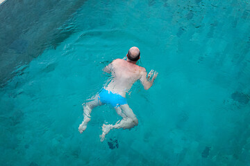 Image showing Balding man swimming in clean blue water