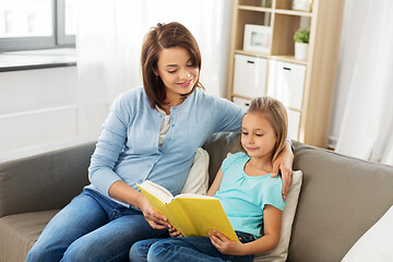 Image showing happy girl with mother reading book at home