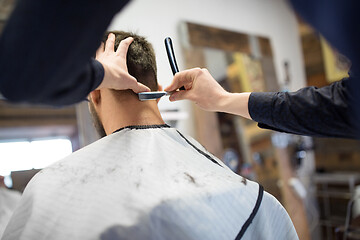 Image showing man and barber with straight razor shaving hair