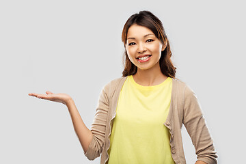 Image showing happy asian woman holding something on hand