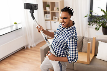 Image showing man in headphones with vacuum cleaner at home