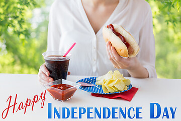 Image showing close up of woman eating hot dog with coca cola