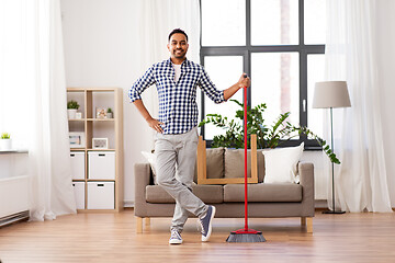 Image showing smiling indian man with broom cleaning at home