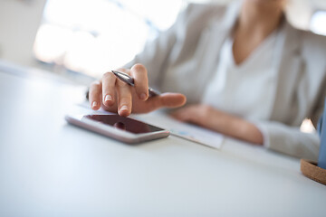 Image showing hand of businesswoman using smartphone at office