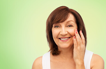 Image showing portrait of smiling senior woman touching her face