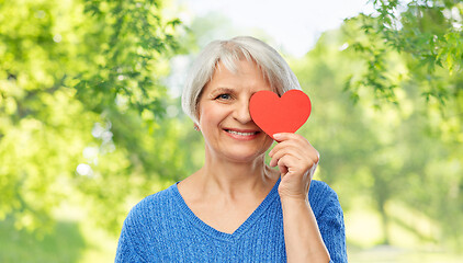 Image showing smiling senior woman covering eye with red heart