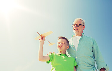 Image showing senior man and boy with toy airplane over sky