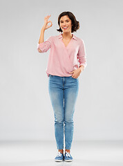 Image showing young woman in striped shirt and jeans showing ok