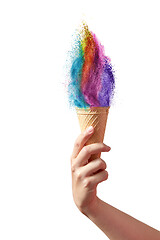 Image showing Ice cream from rainbow dust splash in a waffle cone in a hand.