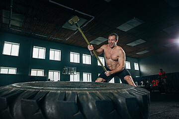 Image showing Shirtless man flipping heavy tire at gym