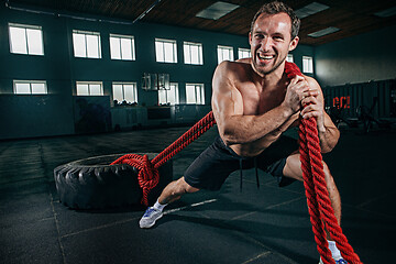 Image showing Shirtless man flipping heavy tire at gym