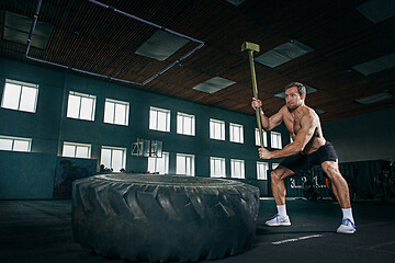 Image showing Shirtless man flipping heavy tire at gym