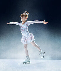 Image showing Little girl figure skating at the indoor ice arena.