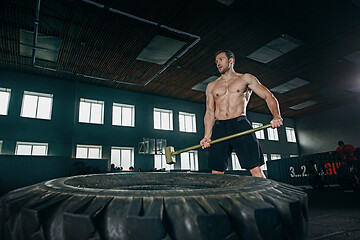 Image showing Shirtless man flipping heavy tire at gym