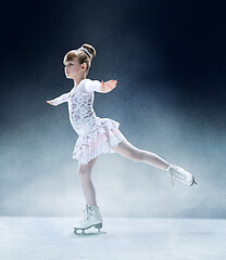 Image showing Little girl figure skating at the indoor ice arena.