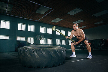 Image showing Shirtless man flipping heavy tire at gym