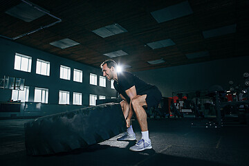 Image showing Shirtless man flipping heavy tire at gym