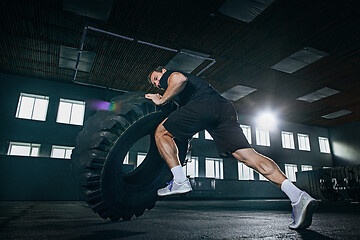 Image showing Shirtless man flipping heavy tire at gym