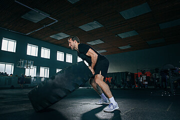 Image showing Shirtless man flipping heavy tire at gym