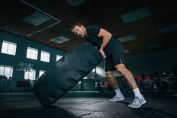 Image showing Shirtless man flipping heavy tire at gym