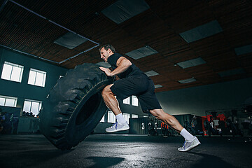 Image showing Shirtless man flipping heavy tire at gym