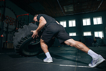 Image showing Shirtless man flipping heavy tire at gym