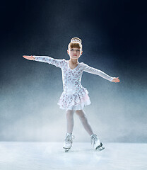 Image showing Little girl figure skating at the indoor ice arena.