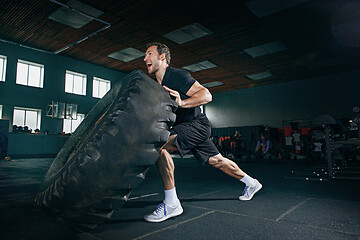 Image showing Shirtless man flipping heavy tire at gym