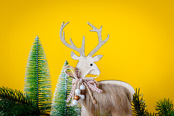 Image showing Christmas decoration wooden reindeer with fir trees on yellow ba