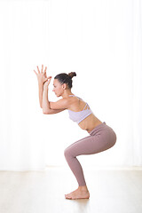 Image showing Portrait of gorgeous active sporty young woman practicing yoga in studio. Beautiful girl practice Garurasana, eagle yoga pose. Healthy active lifestyle, working out indoors in gym