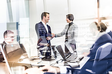 Image showing Confident business people shaking hands in moder corporate office.