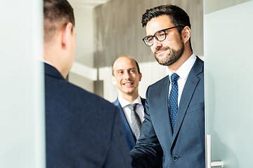 Image showing Group of confident business people greeting with a handshake at business meeting in modern office or closing the deal agreement by shaking hands.